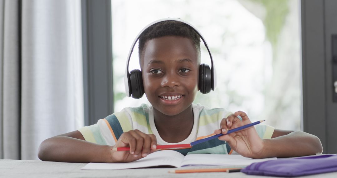 Young Student Wearing Headphones Studying at Home Focused on Homework