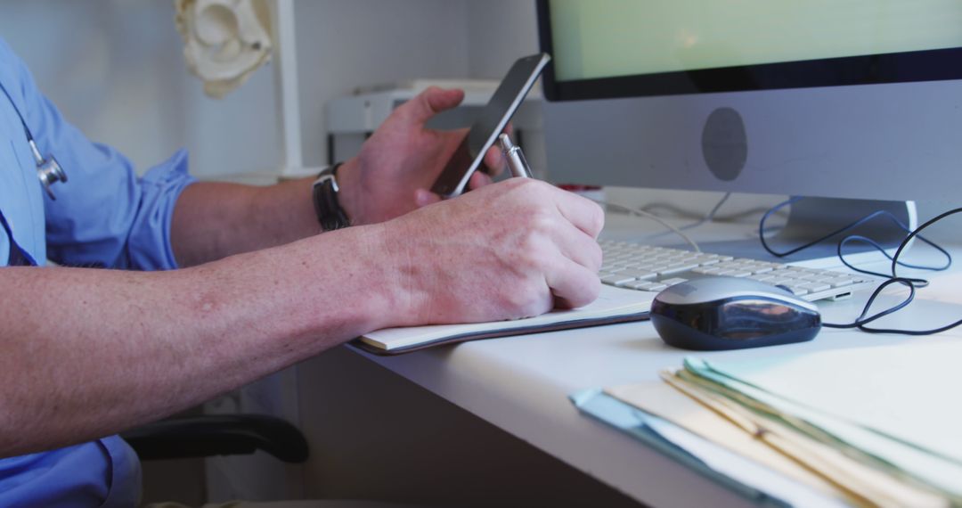 Doctor Using Smartphone and Taking Notes in Medical Office
