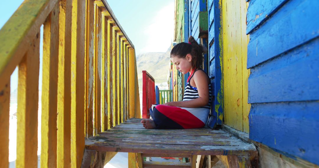 Young Girl Reading on Colorful Beach Hut Staircase - Free Images, Stock Photos and Pictures on Pikwizard.com