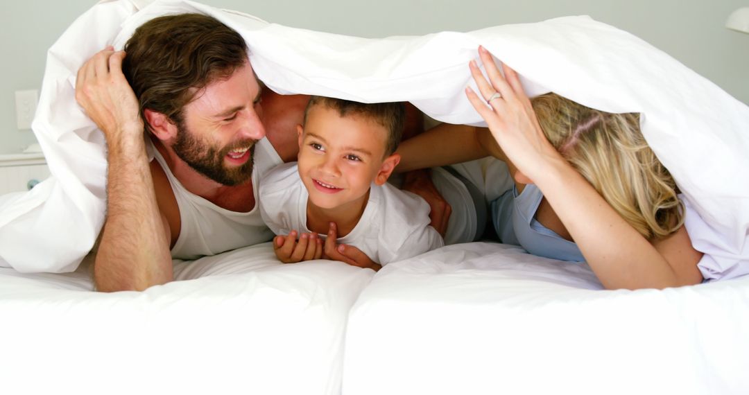 Happy Family Playing Under Blanket on Bed in Bright Morning Light - Free Images, Stock Photos and Pictures on Pikwizard.com