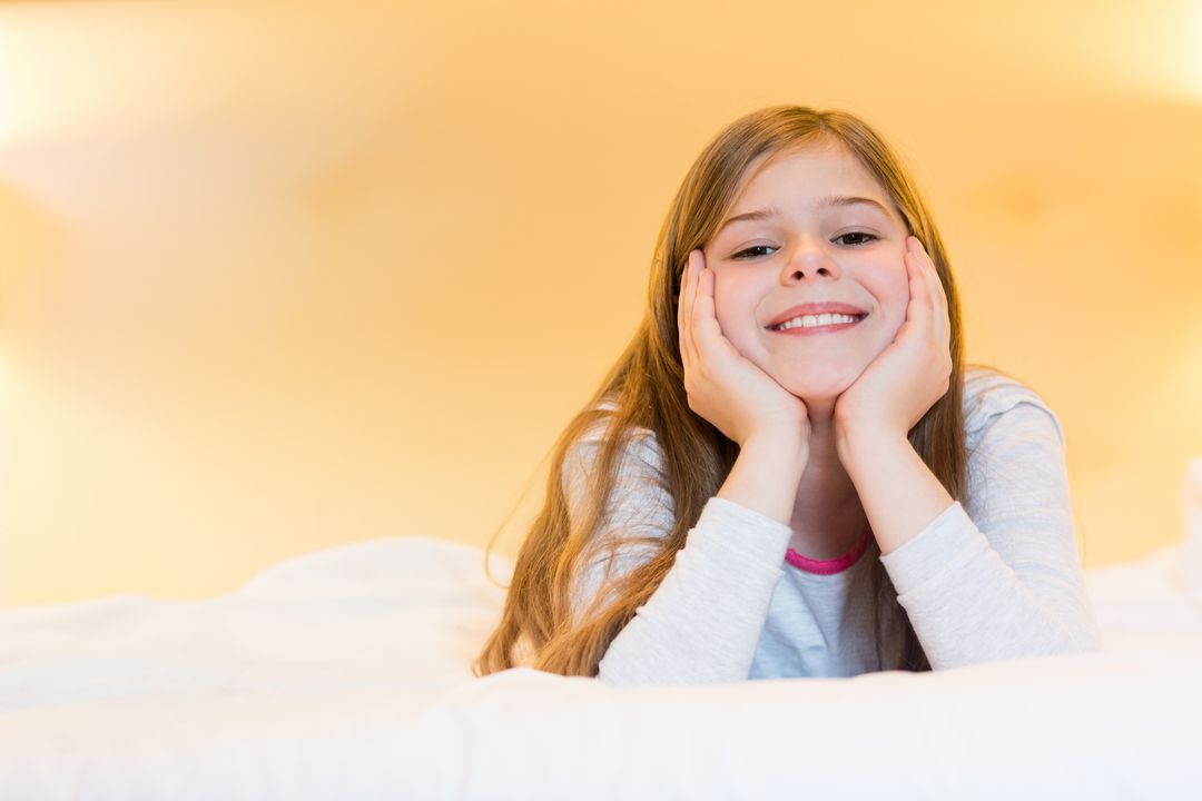 Young Girl Relaxing on White Bed with Bright Smile