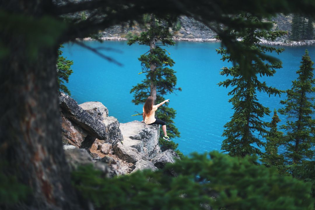 Woman Sitting on Rocky Ledge by Blue Lake - Free Images, Stock Photos and Pictures on Pikwizard.com