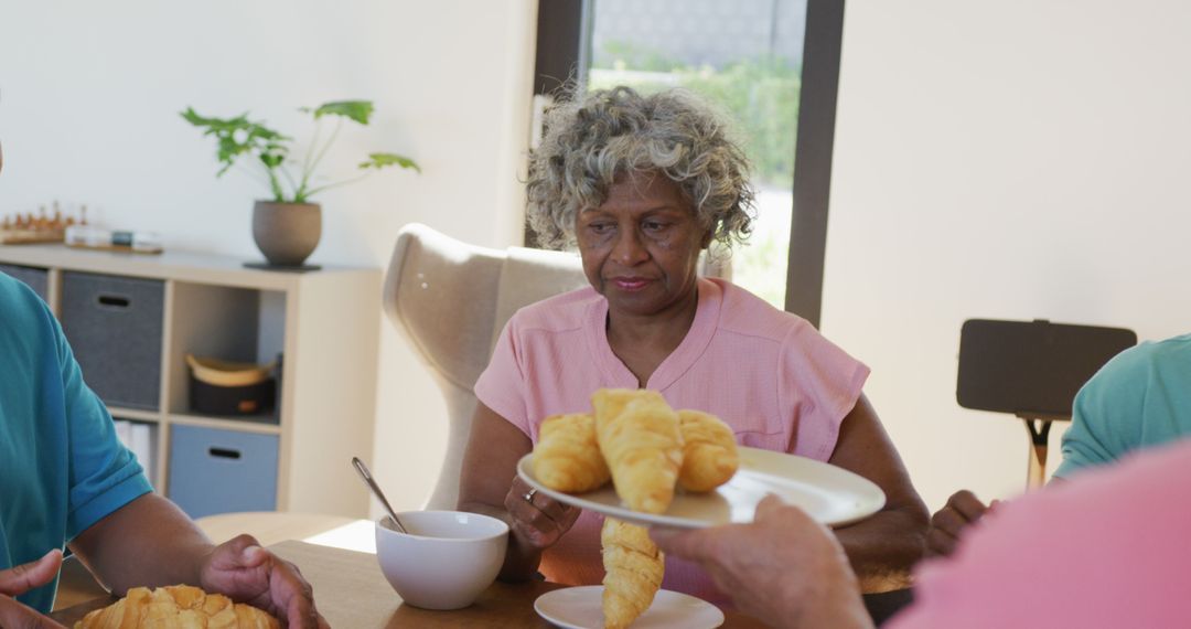 Senior Black Woman Sharing Croissants at Breakfast Table with Family - Free Images, Stock Photos and Pictures on Pikwizard.com