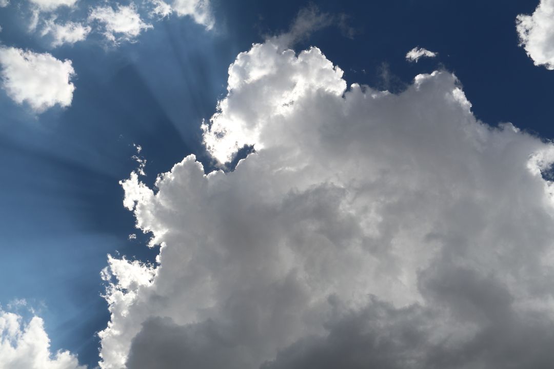 Dramatic Sunlight Rays Shining Through Cumulus Clouds on Clear Blue Sky - Free Images, Stock Photos and Pictures on Pikwizard.com