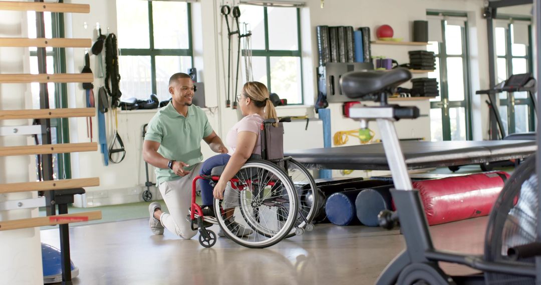 Kneeling Therapist Assisting Wheelchair User During One-on-One Rehabilitation Session