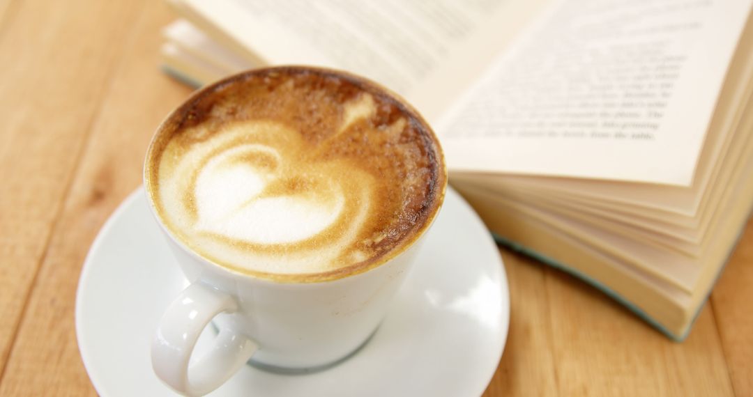 Latte with heart pattern and open book on wooden table - Free Images, Stock Photos and Pictures on Pikwizard.com