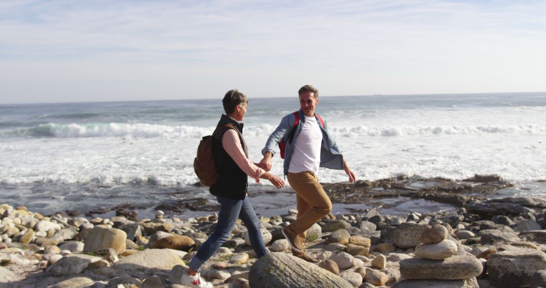 Couple Holding Hands Walking on Rocky Beach - Free Images, Stock Photos and Pictures on Pikwizard.com