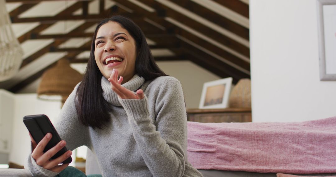 Biracial woman using smartphone and smiling in living room - Free Images, Stock Photos and Pictures on Pikwizard.com