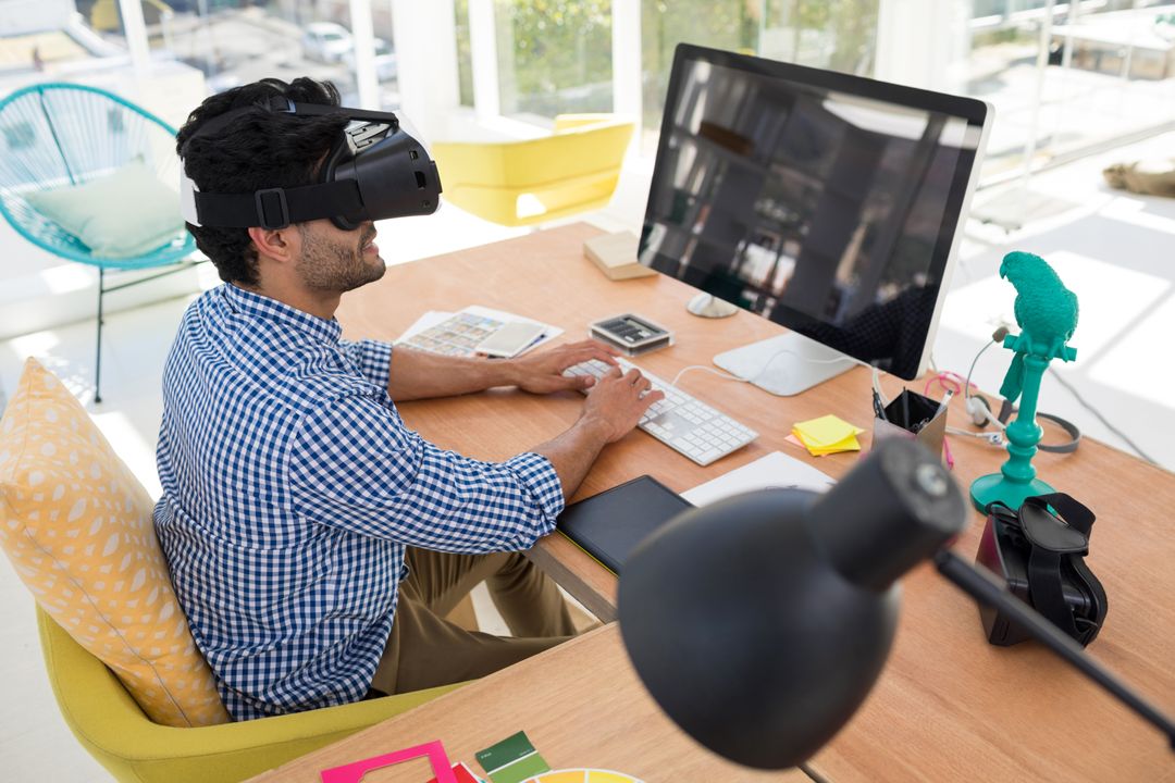 Graphic designer in virtual reality headset working on computer at desk - Free Images, Stock Photos and Pictures on Pikwizard.com