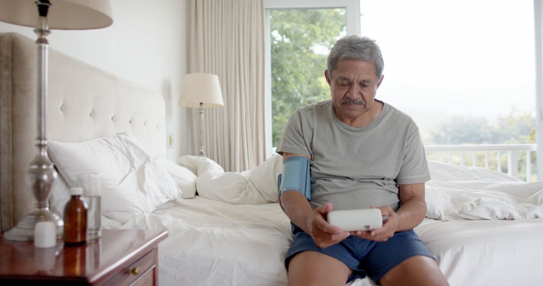 Senior Man Monitoring Blood Pressure at Home, Sitting on Bed - Free Images, Stock Photos and Pictures on Pikwizard.com