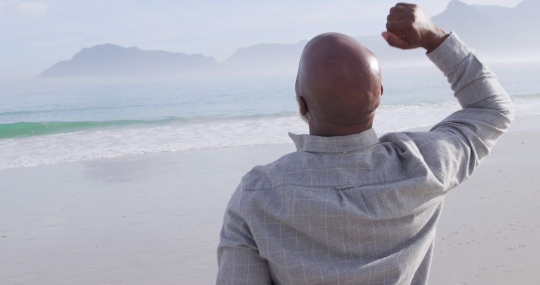 Relaxed Man Enjoying Peaceful Beach Day Raising Arm in Celebration - Free Images, Stock Photos and Pictures on Pikwizard.com