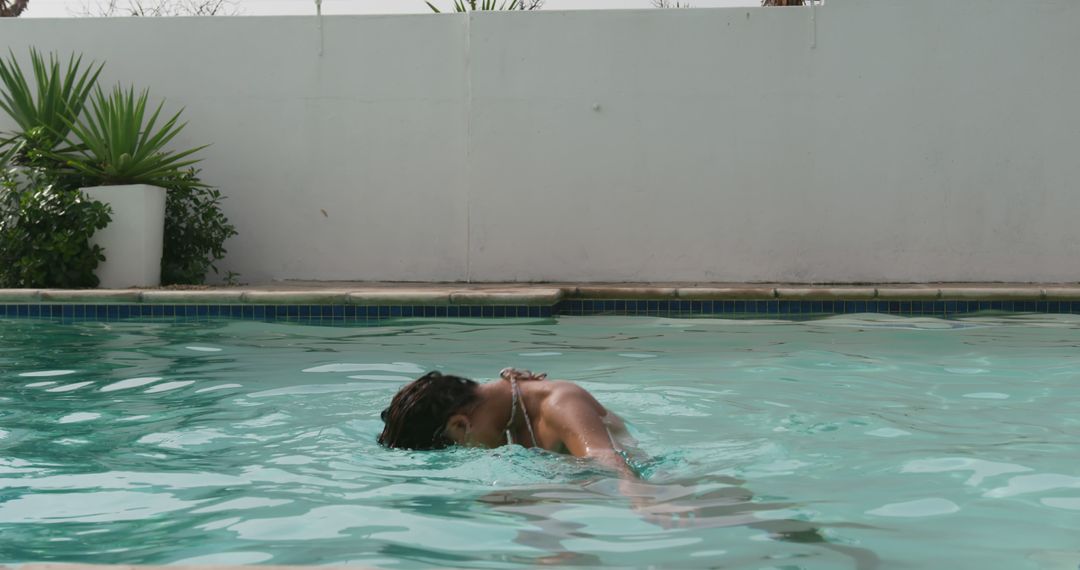 Relaxed Woman Enjoying a Swim in Outdoor Pool on a Sunny Day - Free Images, Stock Photos and Pictures on Pikwizard.com