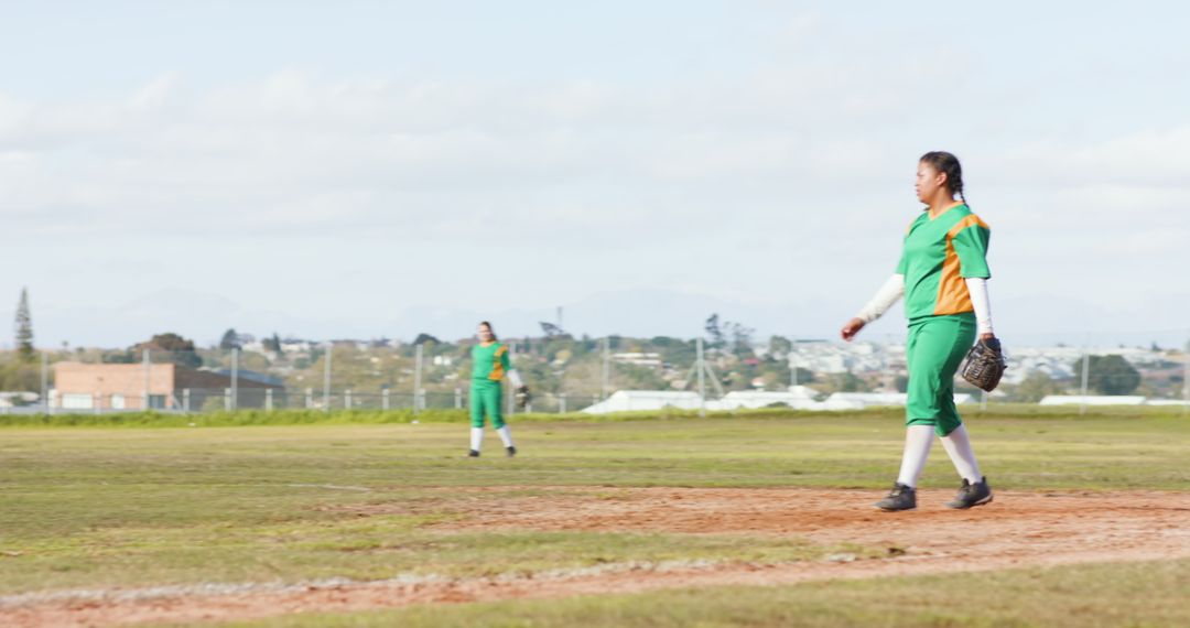 Teammates in Green and Orange Uniforms on Softball Field