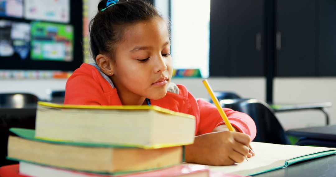 Young Girl Studying Diligently with Stack of Books in Classroom