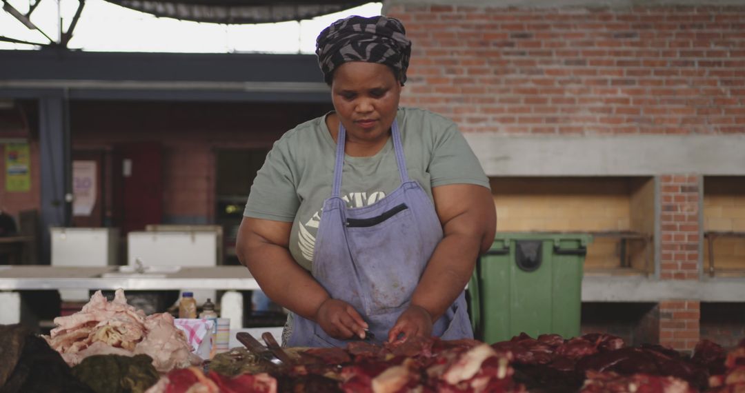African female butcher skillfully preparing fresh meat in market