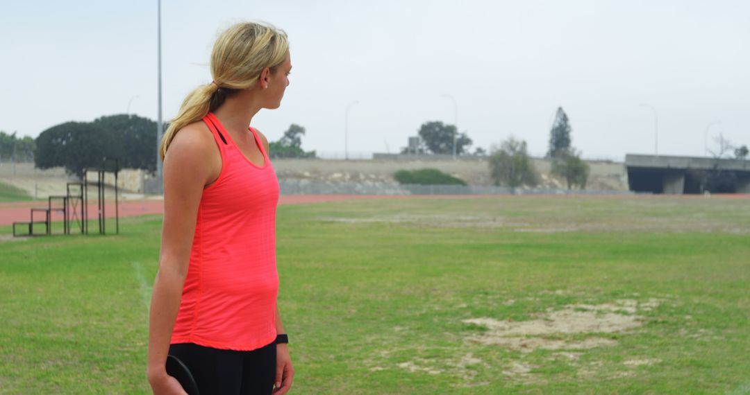 Female Athlete in Bright Tank Top Standing on Open Field - Free Images, Stock Photos and Pictures on Pikwizard.com