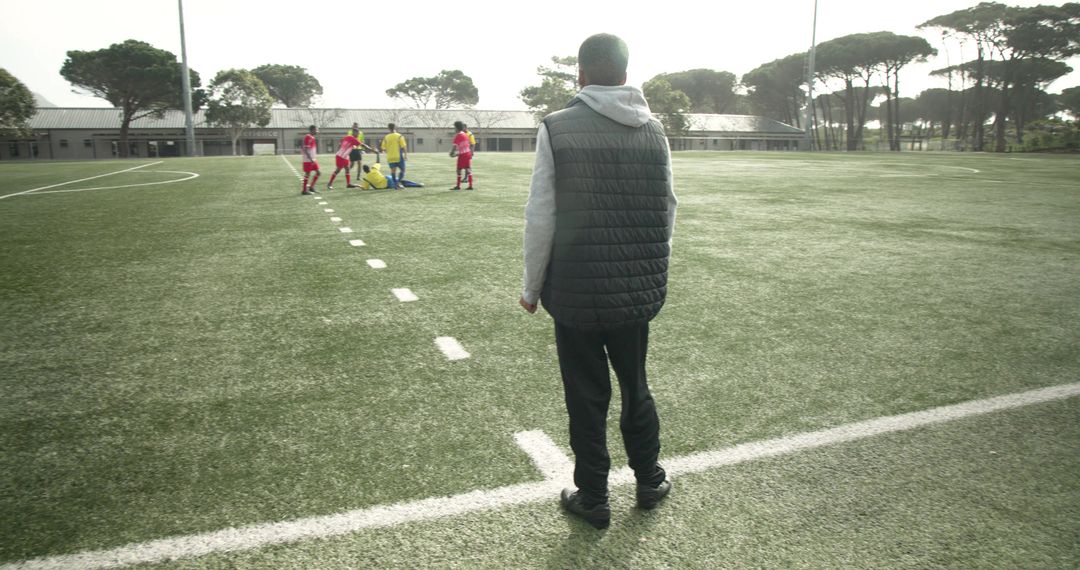 Soccer Coach Watching Players Practice on Sunny Field