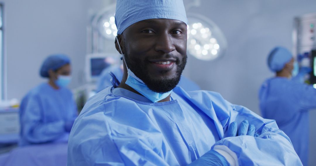 Portrait of african american male surgeon standing in operating theatre smiling to camera - Free Images, Stock Photos and Pictures on Pikwizard.com