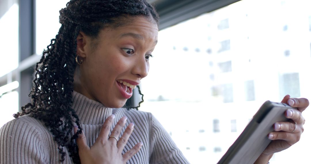 Surprised African American Woman Reacting to Tablet Message While Holding Device by Window