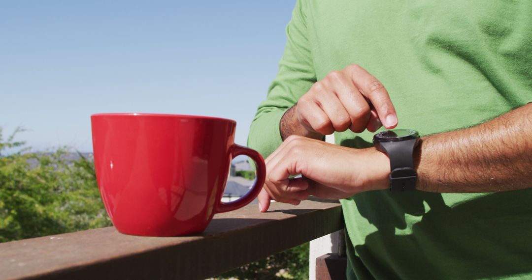 Person Checking Smartwatch with Red Mug on Balcony - Free Images, Stock Photos and Pictures on Pikwizard.com