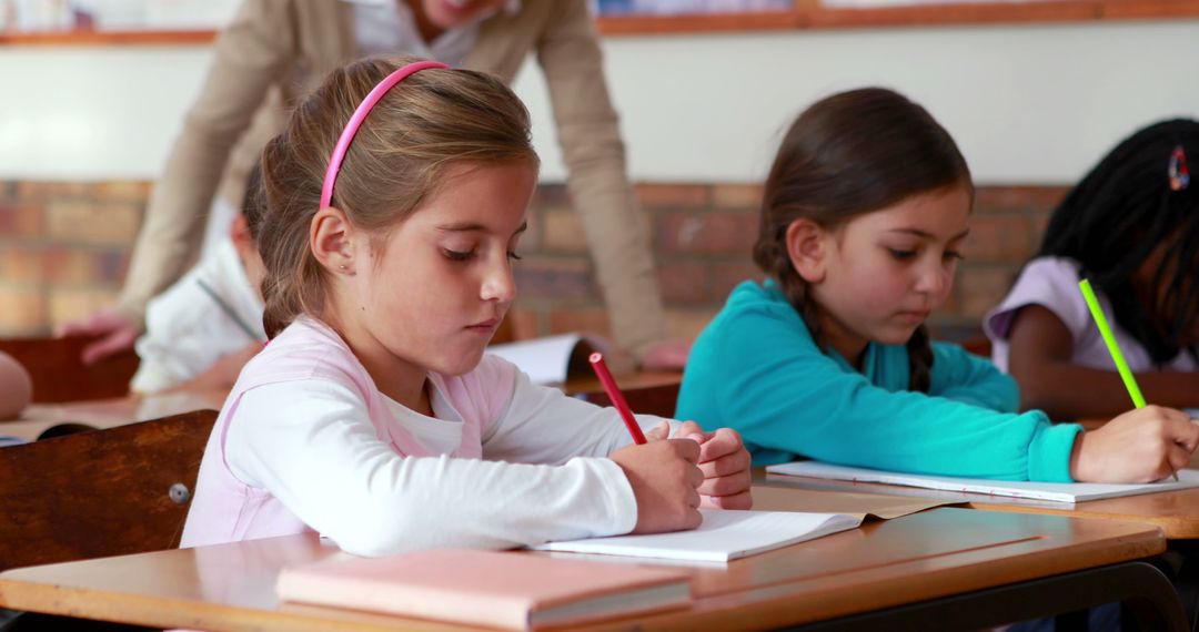 Young Schoolgirls Focused on Writing in Classroom - Free Images, Stock Photos and Pictures on Pikwizard.com