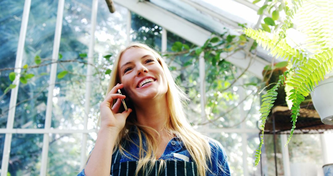 Young Woman Talking on Phone in Vibrant Greenhouse - Free Images, Stock Photos and Pictures on Pikwizard.com