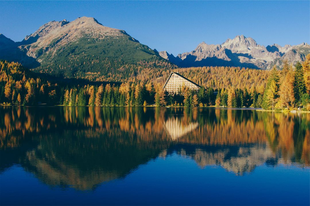 Idyllic Mountain Lake with Autumn Trees and Modern Hotel - Free Images, Stock Photos and Pictures on Pikwizard.com