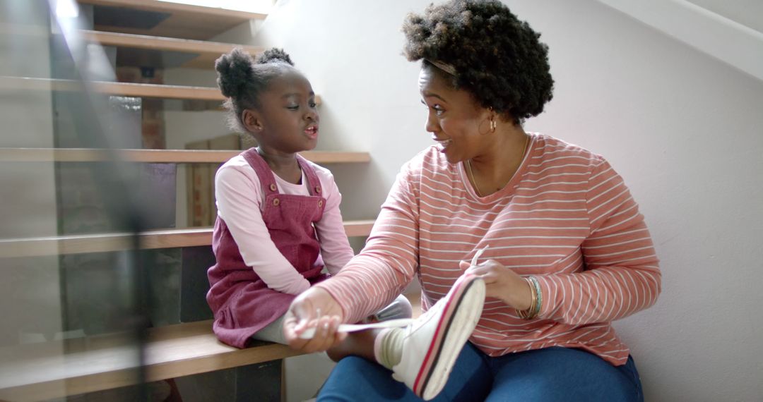 African american mother and daughter tying shoes at home - Free Images, Stock Photos and Pictures on Pikwizard.com