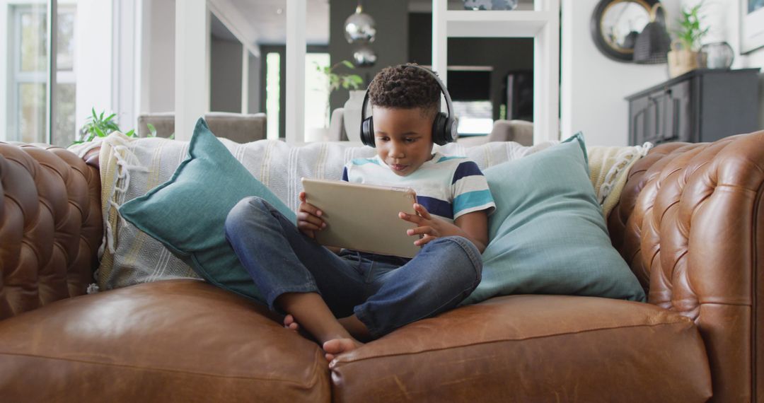 Child Relaxing on Couch with Tablet and Headphones - Free Images, Stock Photos and Pictures on Pikwizard.com