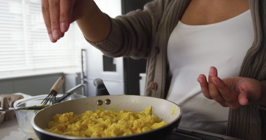 Woman Adding Salt to Scrambled Eggs in Modern Kitchen - Free Images, Stock Photos and Pictures on Pikwizard.com