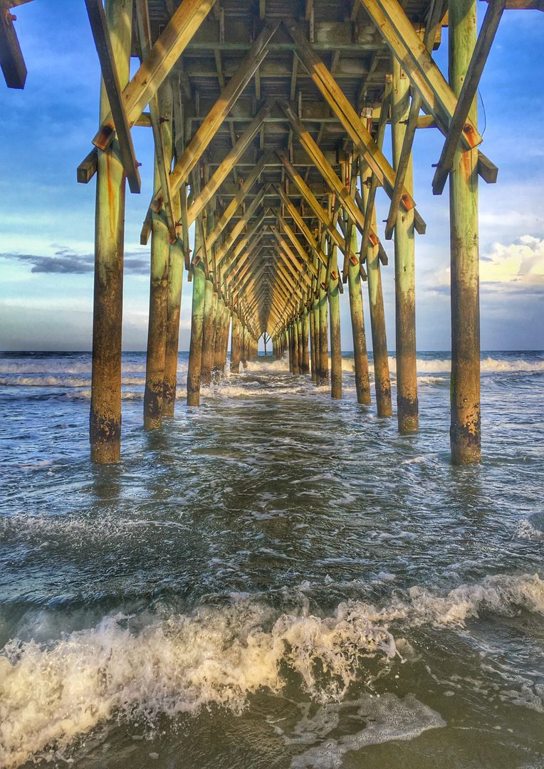 Underneath Wooden Pier Extending over Ocean Waves During Sunset - Free Images, Stock Photos and Pictures on Pikwizard.com