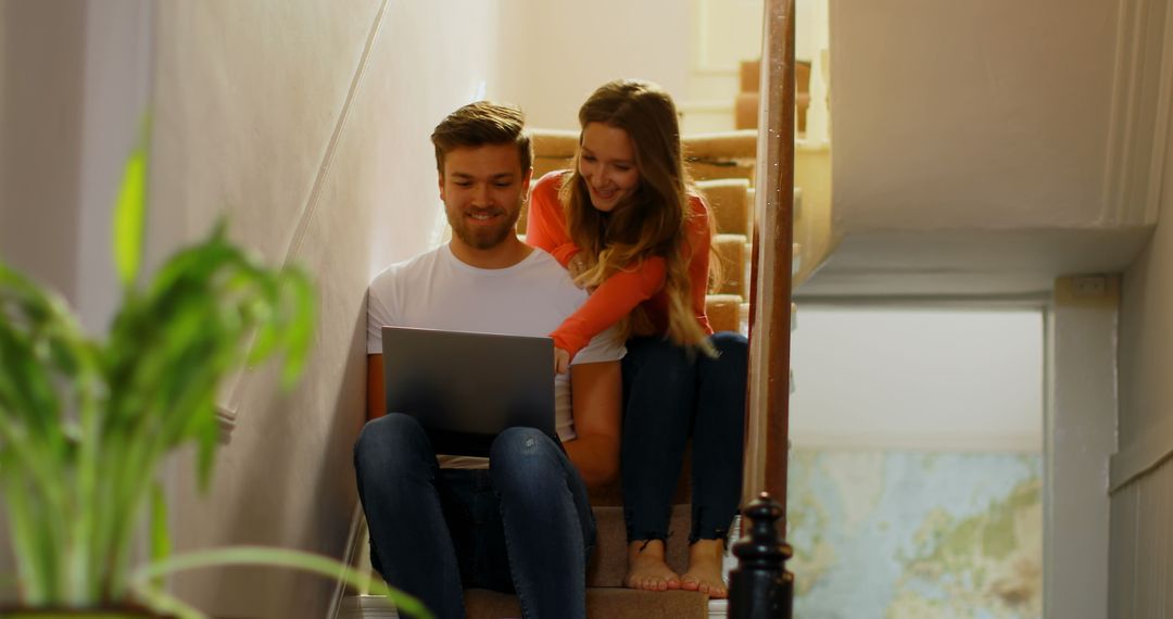 Couple Using Laptop on Home Staircase for Relaxed Discussion