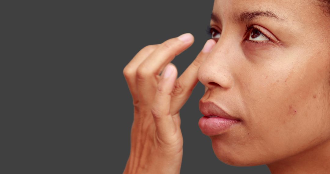 Woman Applying Moisturizer on Face Against Gray Background - Free Images, Stock Photos and Pictures on Pikwizard.com