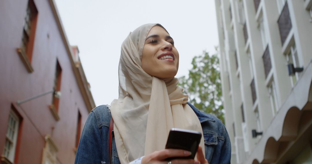 Muslim Woman Walking In Urban Environment While Using Smartphone - Free Images, Stock Photos and Pictures on Pikwizard.com