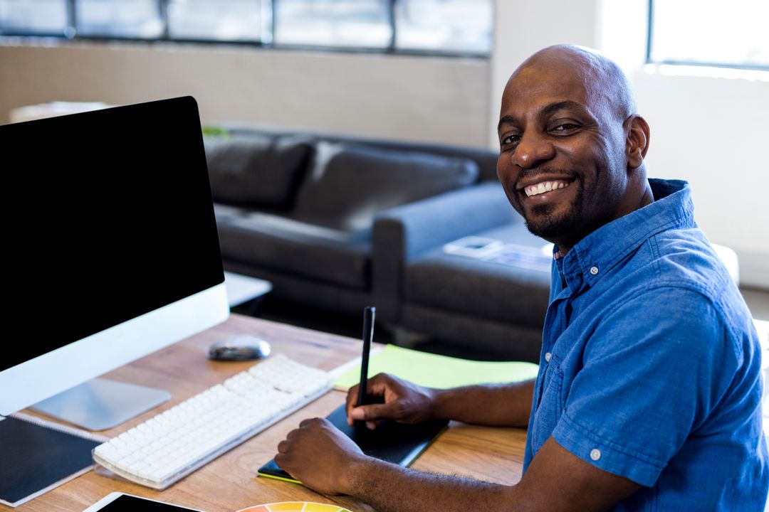 Creative Designer Smiling at Workdesk with Digital Tools