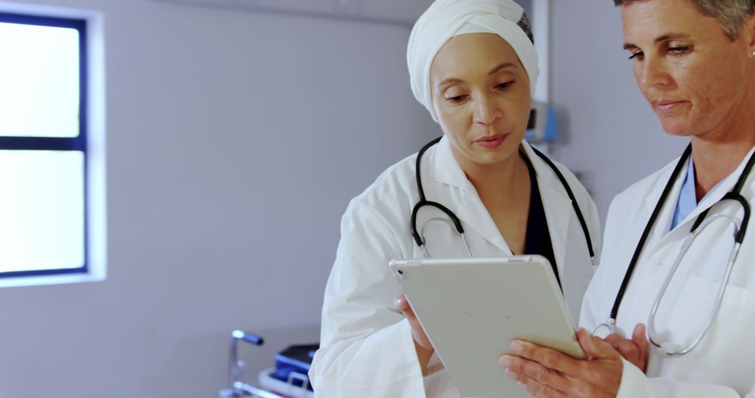 Two Female Doctors Discussing Medical Records with Digital Tablet - Free Images, Stock Photos and Pictures on Pikwizard.com