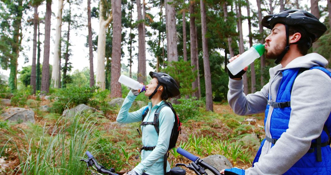 Couple Hydrating After Mountain Biking in Forest - Free Images, Stock Photos and Pictures on Pikwizard.com