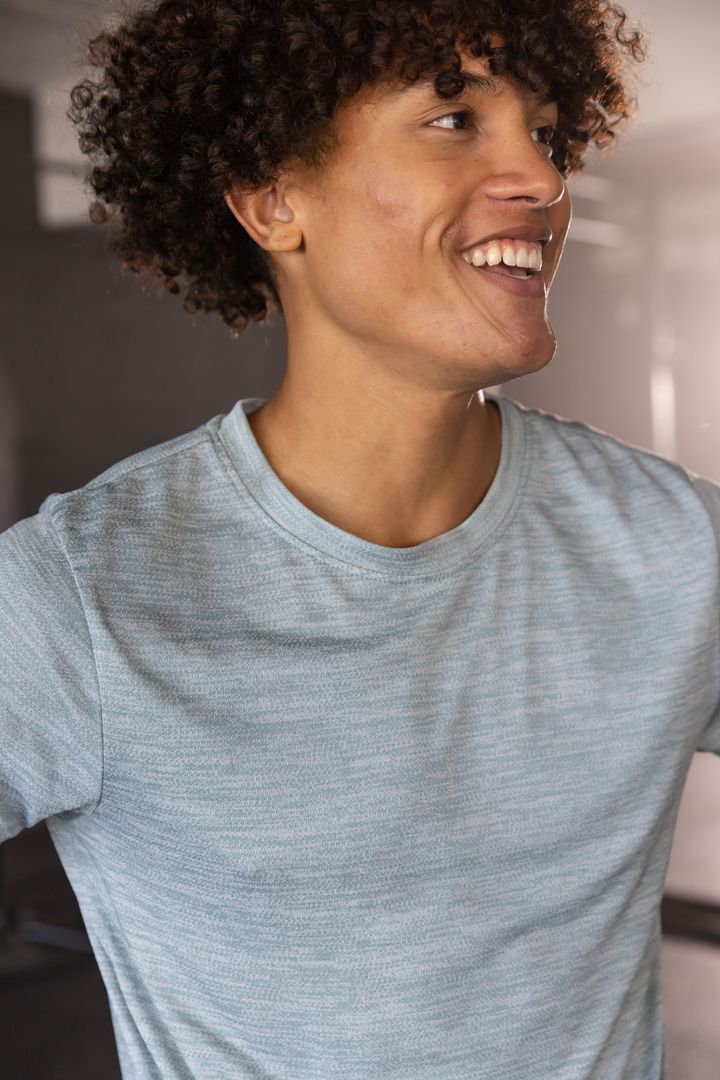 Curly-haired Person Smiling in Light Grey T-Shirt with Natural Light