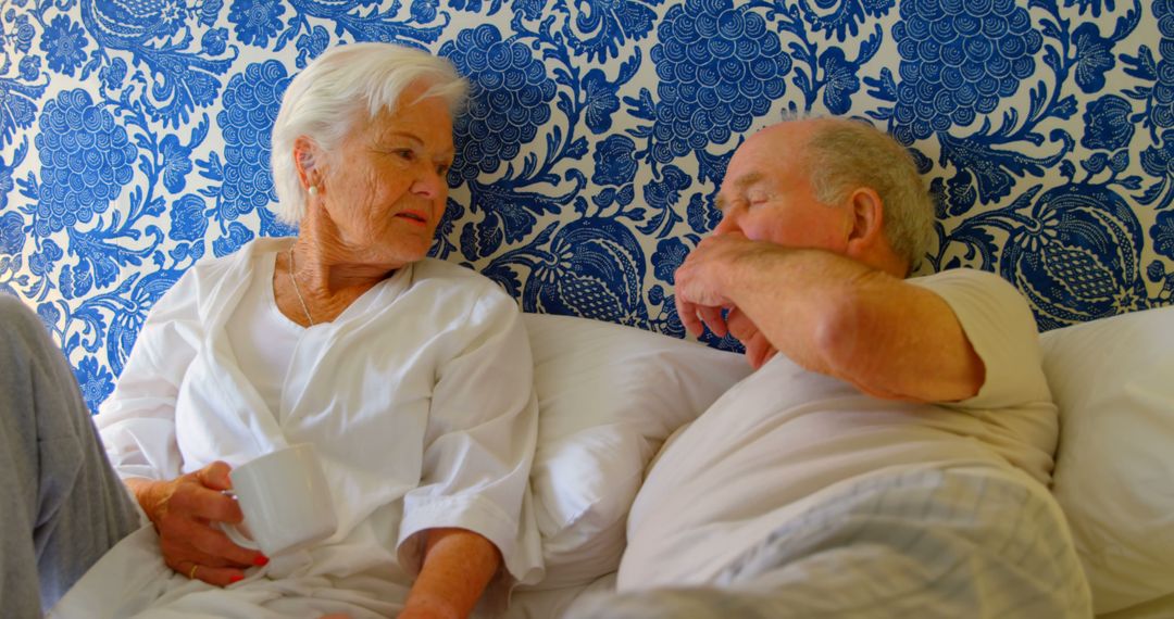 Senior Couple Relaxing in Bed with Floral Wallpaper - Free Images, Stock Photos and Pictures on Pikwizard.com