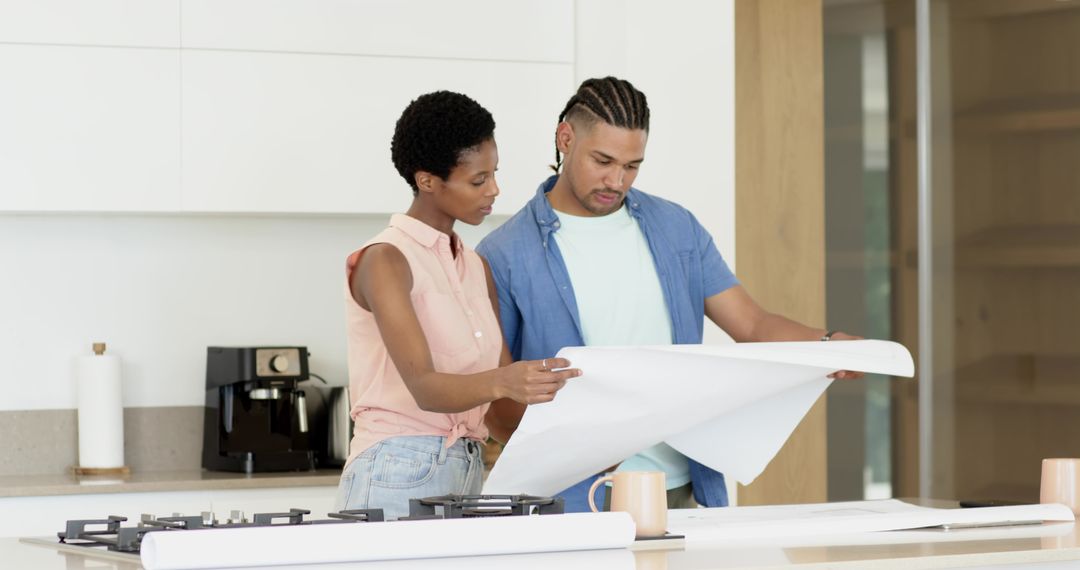 Couple Analyzing Home Blueprints in Modern Kitchen