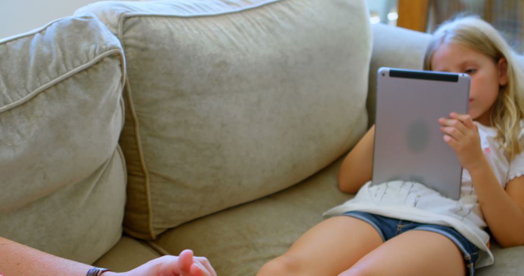 Young Girl Using Tablet While Relaxing on Couch at Home - Free Images, Stock Photos and Pictures on Pikwizard.com