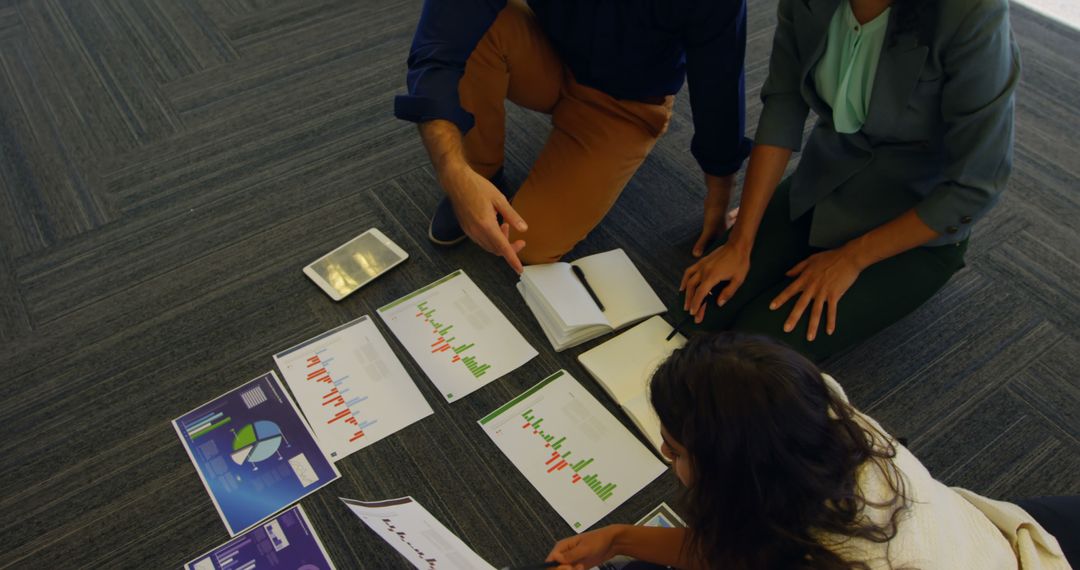 Diverse Professionals Analyzing Business Charts Collaboratively on Floor