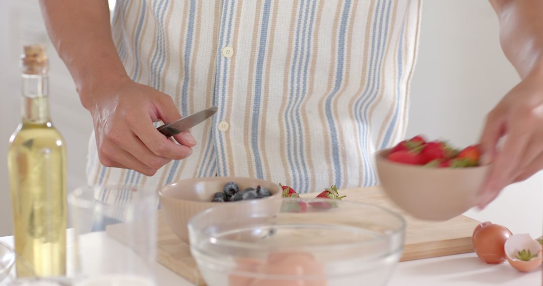 Preparing Fresh Salad with Strawberries and Blueberries in Bright Kitchen