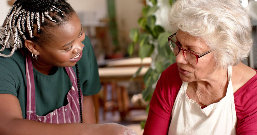 Young caregiver assisting senior woman in kitchen activity - Free Images, Stock Photos and Pictures on Pikwizard.com