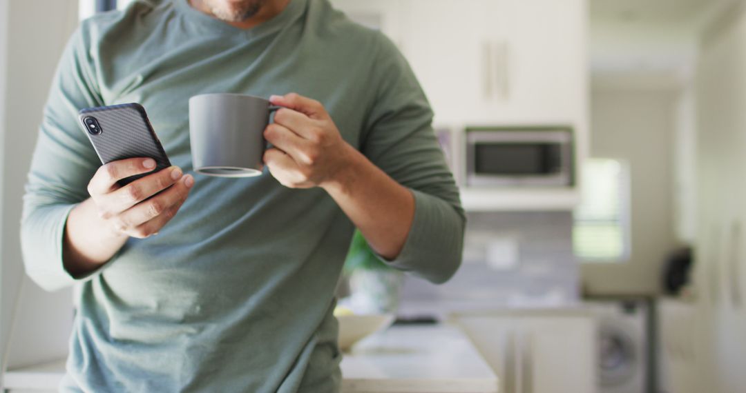 Man drinking coffee while using smartphone in modern kitchen - Free Images, Stock Photos and Pictures on Pikwizard.com