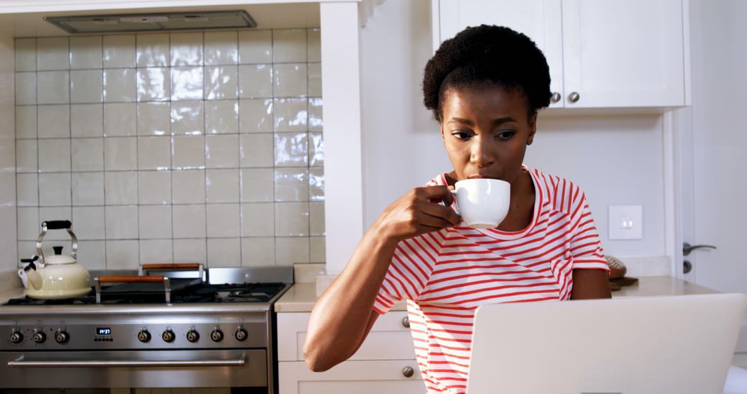 Woman Drinking Coffee While Using Laptop in Modern Kitchen - Free Images, Stock Photos and Pictures on Pikwizard.com