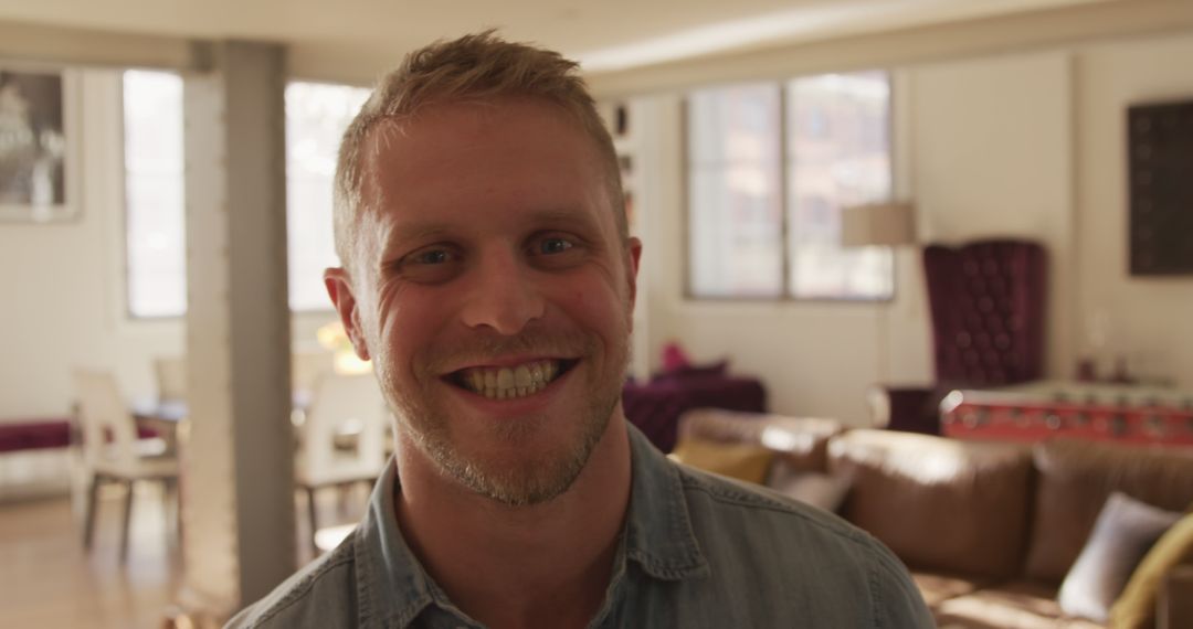 Smiling man with casual outfit in modern living room with natural light - Free Images, Stock Photos and Pictures on Pikwizard.com