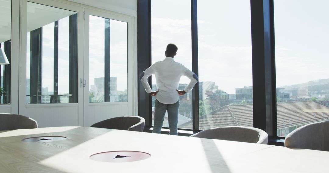 Confident Businessman Standing by Office Window - Free Images, Stock Photos and Pictures on Pikwizard.com