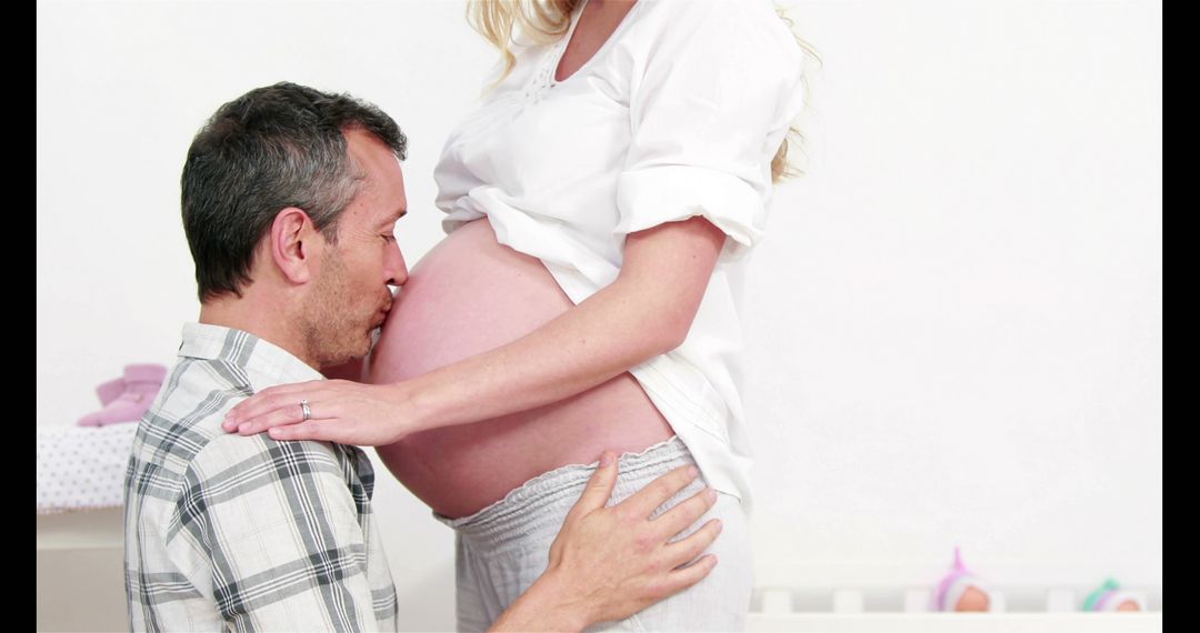 Man kissing belly of his pregnant wife at home - Free Images, Stock Photos and Pictures on Pikwizard.com