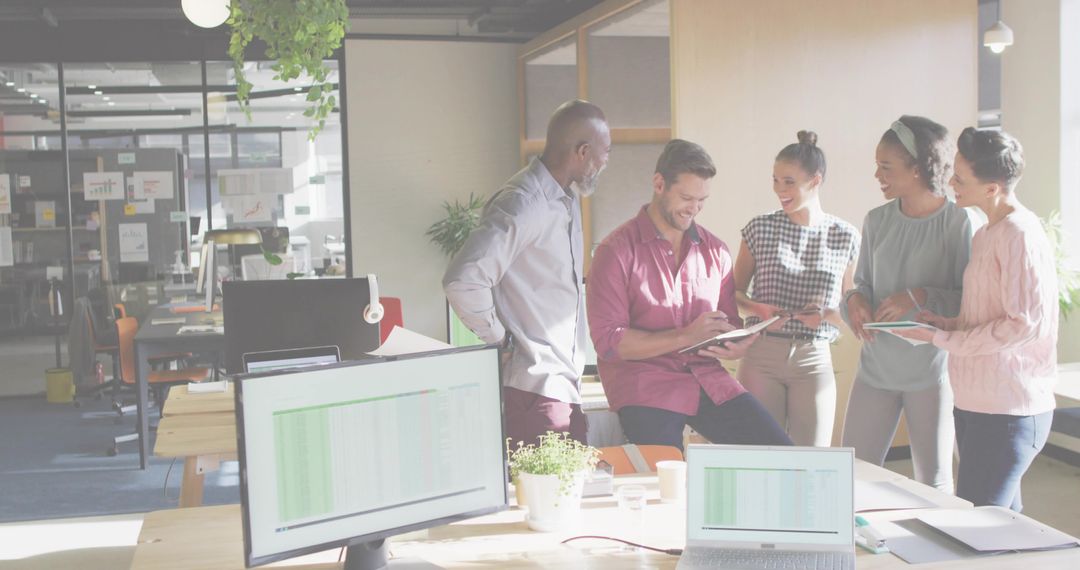 Team collaborating around tablet in sunlit open office, brainstorming and reviewing data